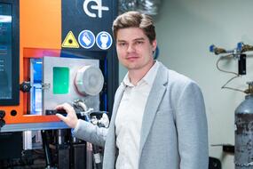 Станислав Чернышихин стоит рядом с 3D-принтером, на котором печатали электрический вольфрамовый нагреватель