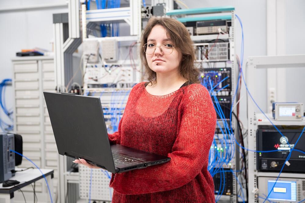 Елизавета Глазкова стоит в квантовой лаборатории с компьютером